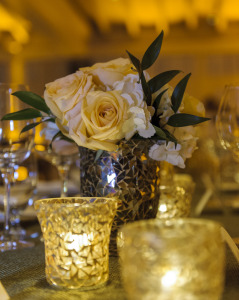 Peach Roses and white hydrangeas in mosaic vase with gold mosaic votive candles keep the room warm